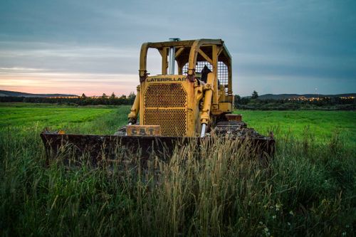 Free Old shabby agricultural tractor in grass of agricultural field in farm in village in evening Stock Photo