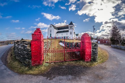 Free Gate against church facade under cloudy sky in countryside Stock Photo
