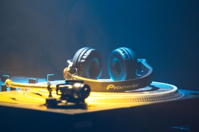 Headphones resting on a DJ deck under neon light