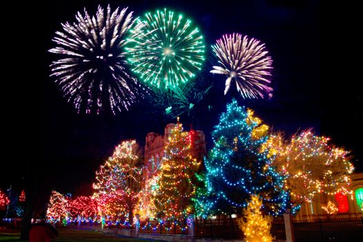 Vibrant fireworks light up the night sky over festive Christmas decorated trees.