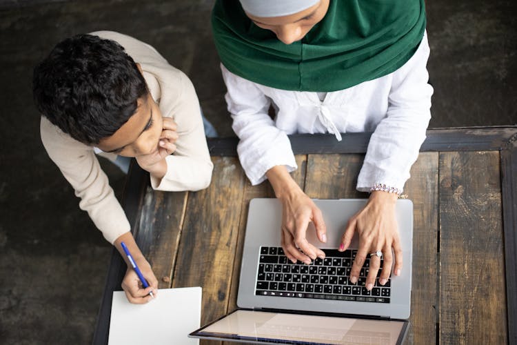 Arabian Mother In Hijab Typing Report On Laptop Near Son