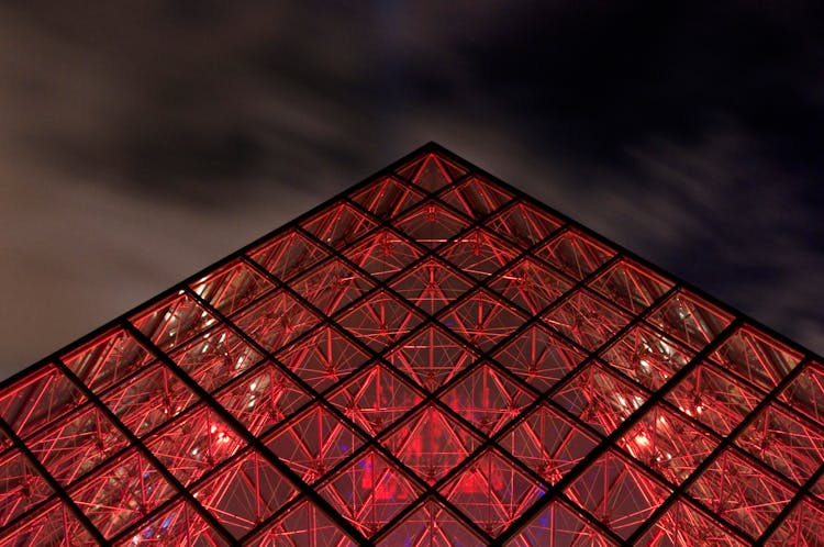 Close-up Of The Tip Of The Louvre Pyramid Illuminated In Bright Red Color 