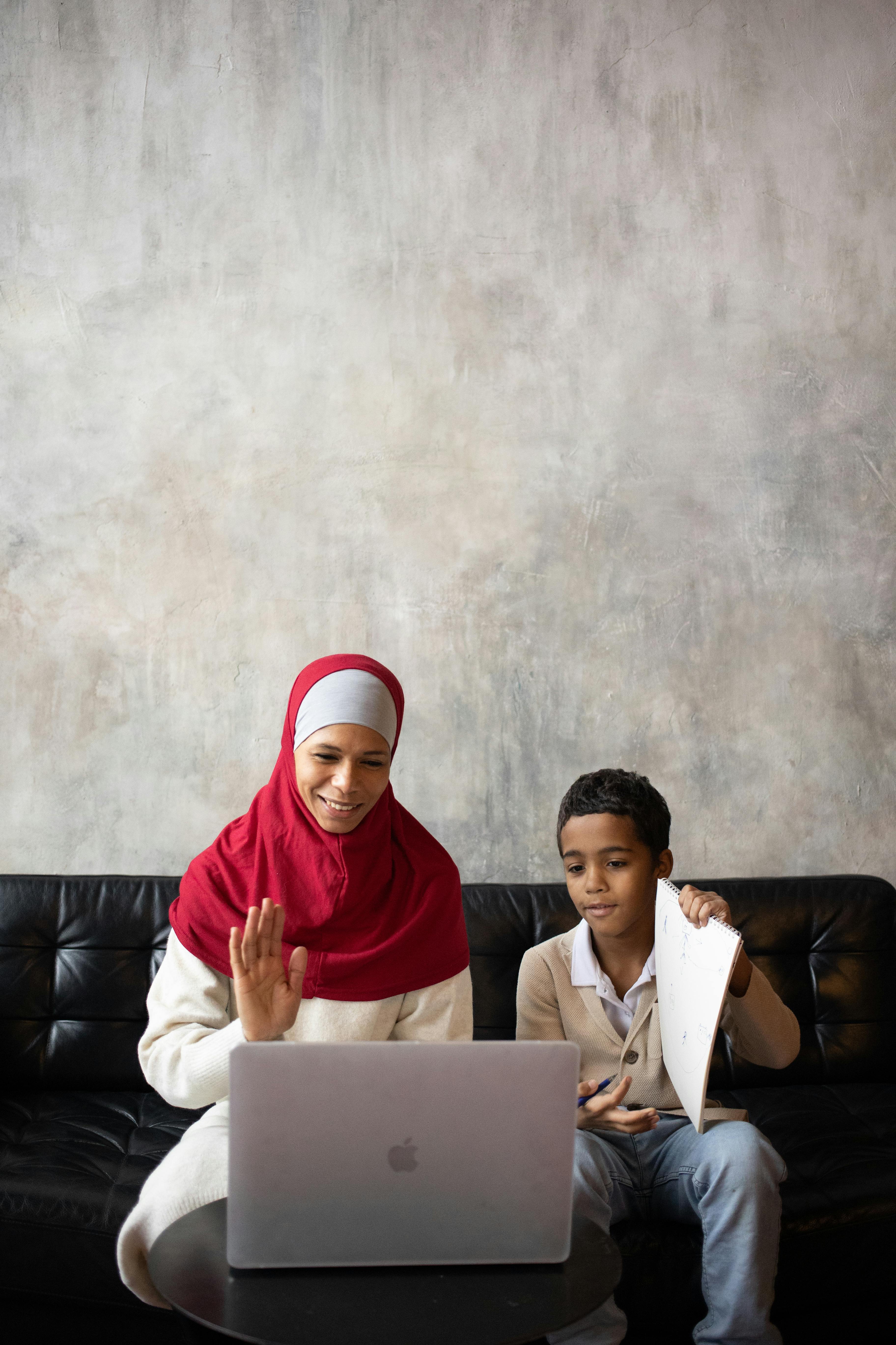 arabian mother in hijab and son with paper using laptop