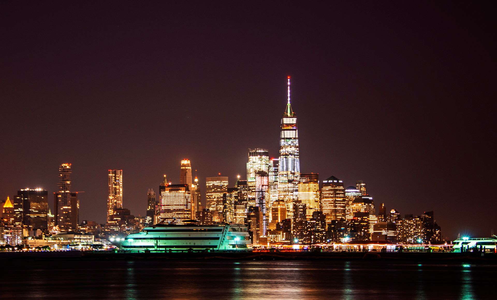 Dazzling New York City skyline with One World Trade Center illuminated at night.