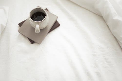 Free Cup of aromatic coffee and notebooks placed on white bed Stock Photo