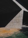 Old concrete bridge in shadow near lawn with dry and fresh grass in daytime