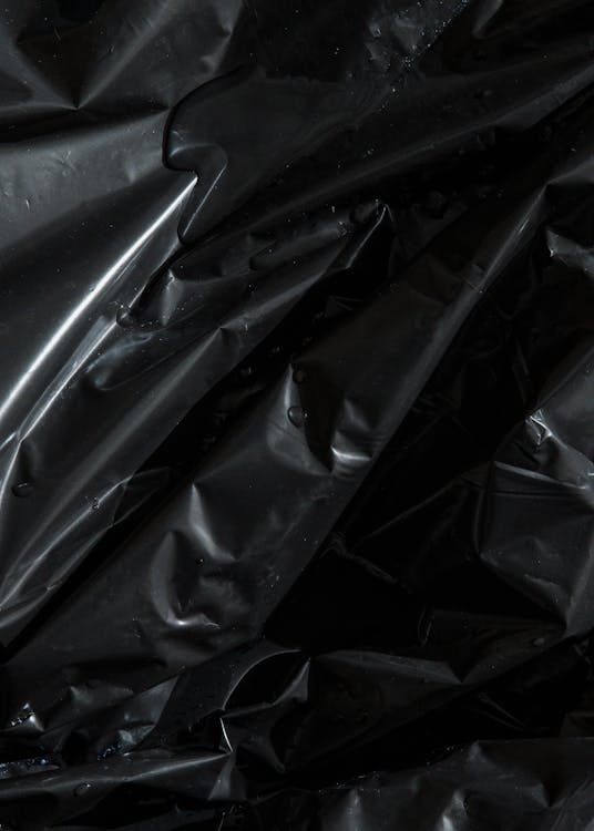 Free From above of smooth surface of black crumpled plastic bag as abstract background Stock Photo