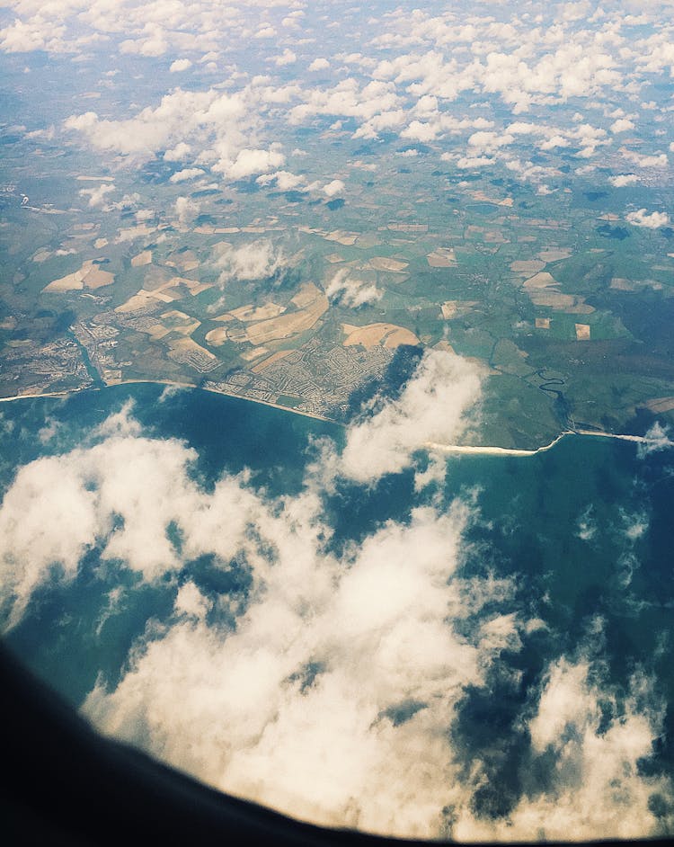 View From Aircraft Window On Green Ground And Blue Sea