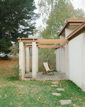 Exterior of concrete house with wooden details and pillars near green lawn with stone steps