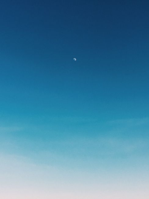 Spectacular scenery of cloudless blue sky with bright moon in summer at sunrise
