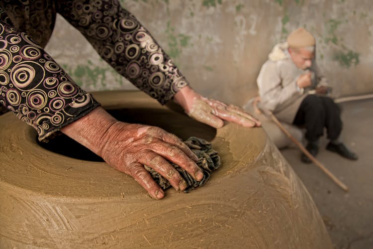 An Elderly Person Wiping A Clay Jar