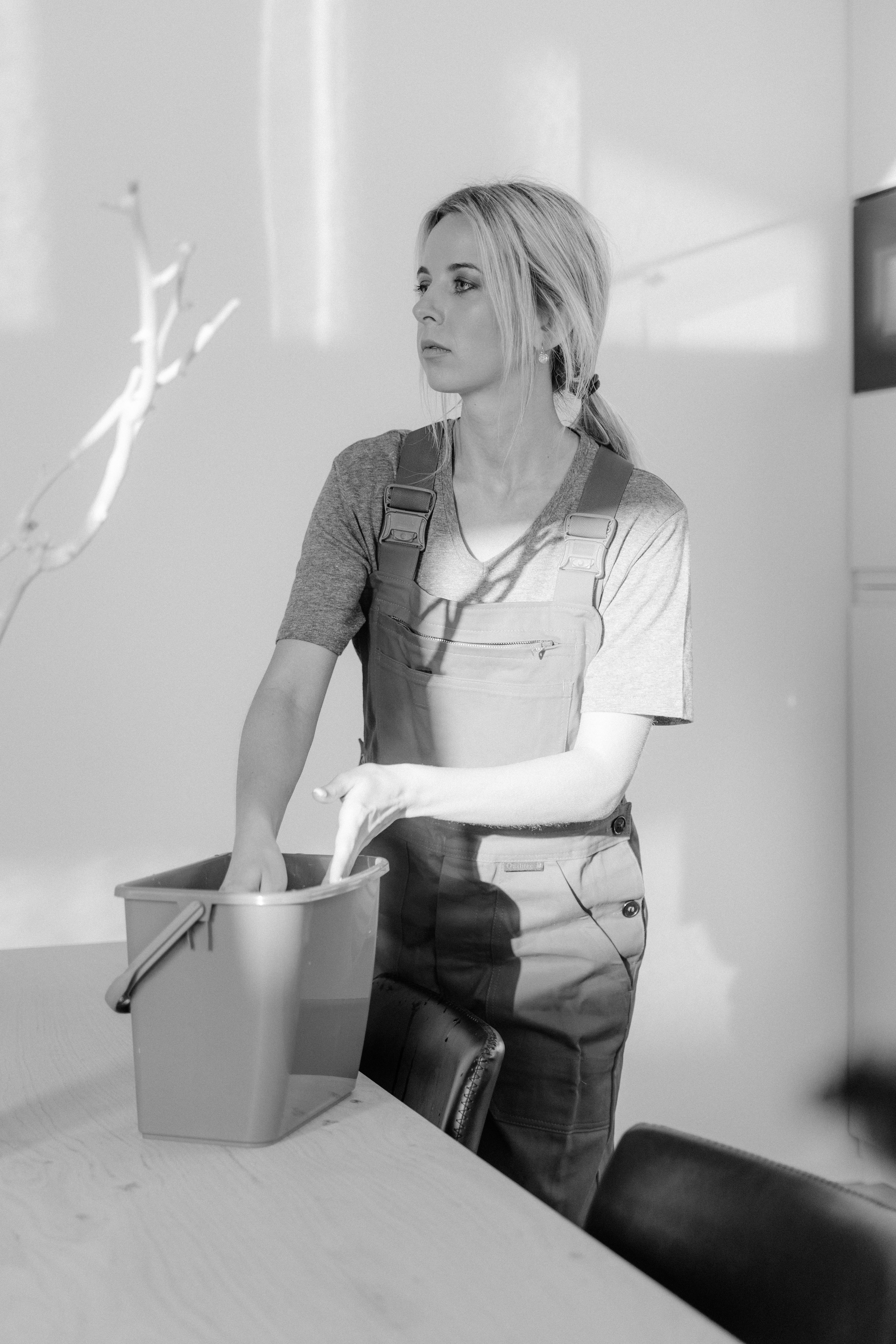 grayscale photo of a woman with hand inside a pail