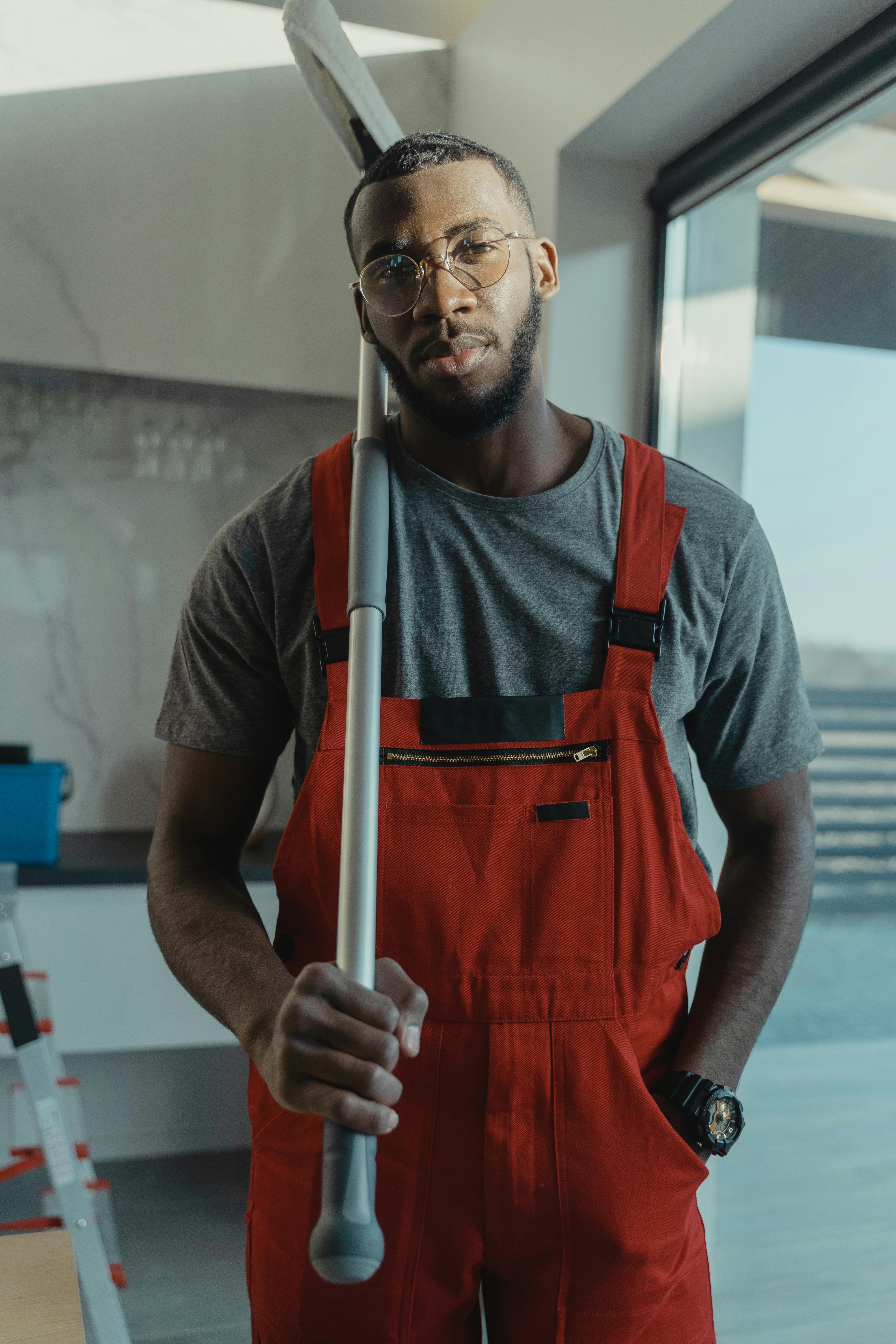 Confident male cleaner posing with cleaning tool in modern interior, showcasing professionalism.