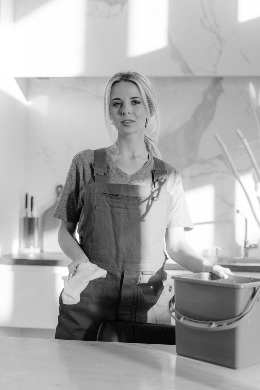 Cleaning team member with supplies standing in a kitchen before starting work