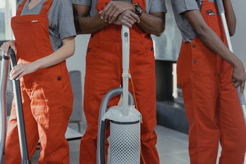 Man in Orange Button Up Shirt Holding Gray and White Polka Dot Handbag