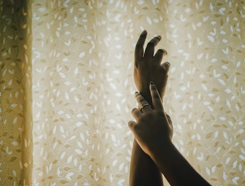 Unrecognizable couple touching hands near window