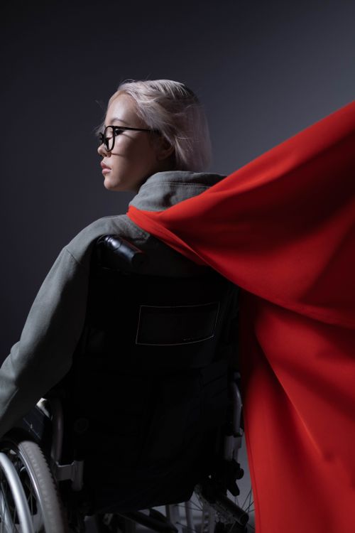 Free Teenager in wheelchair wearing a red cape, representing empowerment and strength. Stock Photo