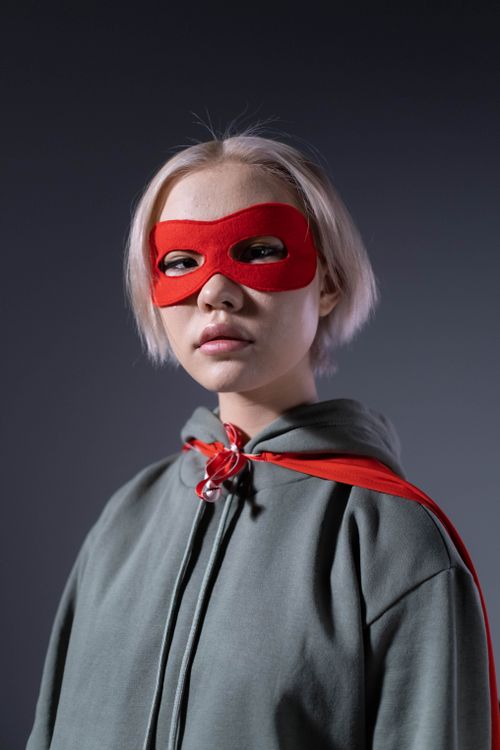 Free Portrait of a teenager wearing a red mask and cape, embodying a superhero persona. Stock Photo