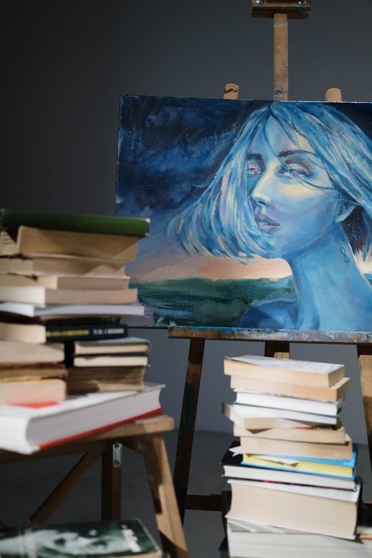 Painting On Easel And Pile Of Books