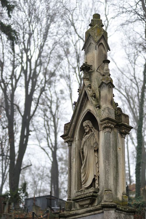Free Gothic stone monument in Lviv cemetery, surrounded by bare trees in winter. Stock Photo