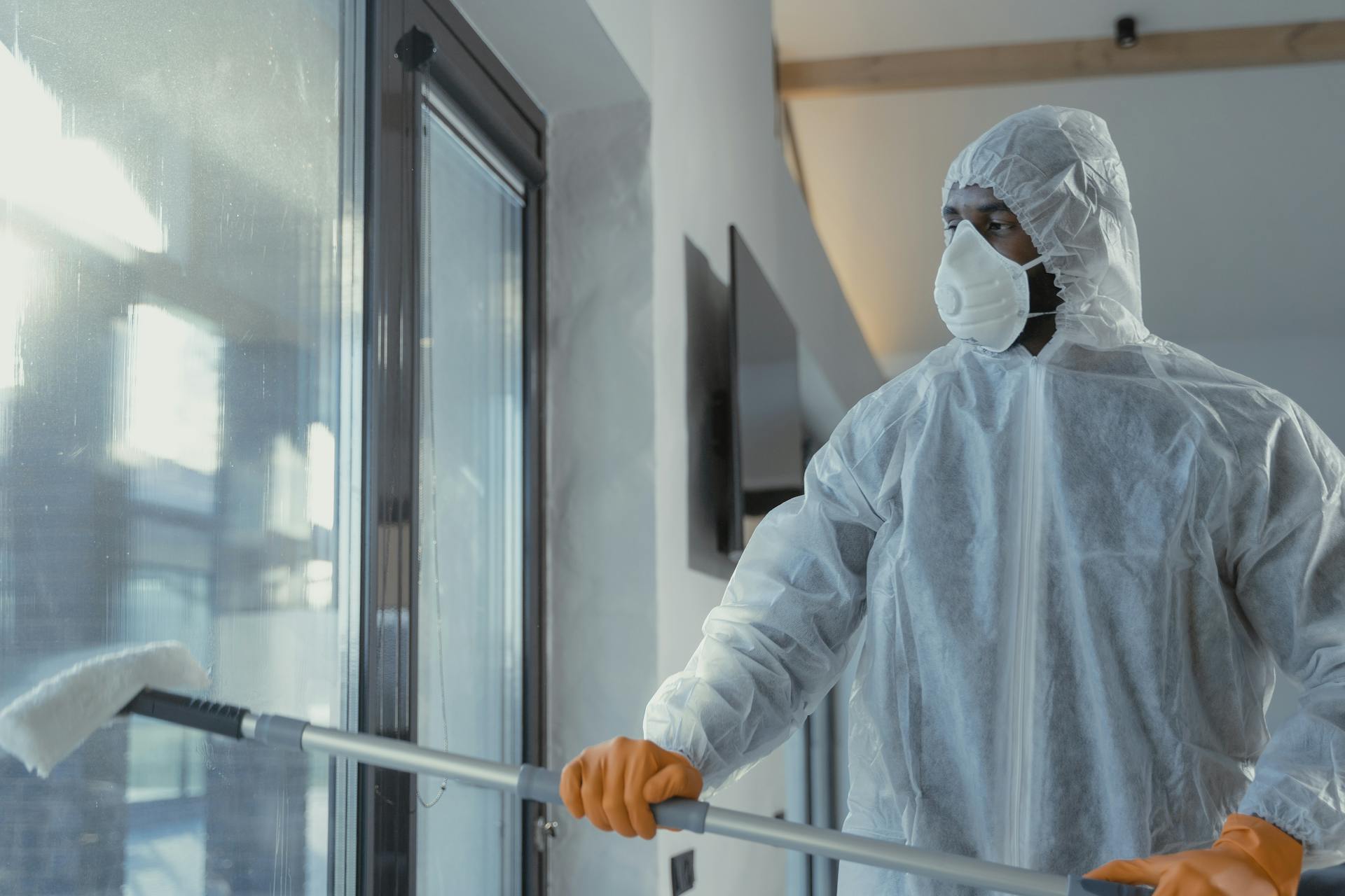 A Man in a Coverall Suit Cleaning a Window