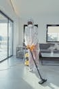 Person in White Protective Suit Holding Vacuum Cleaner