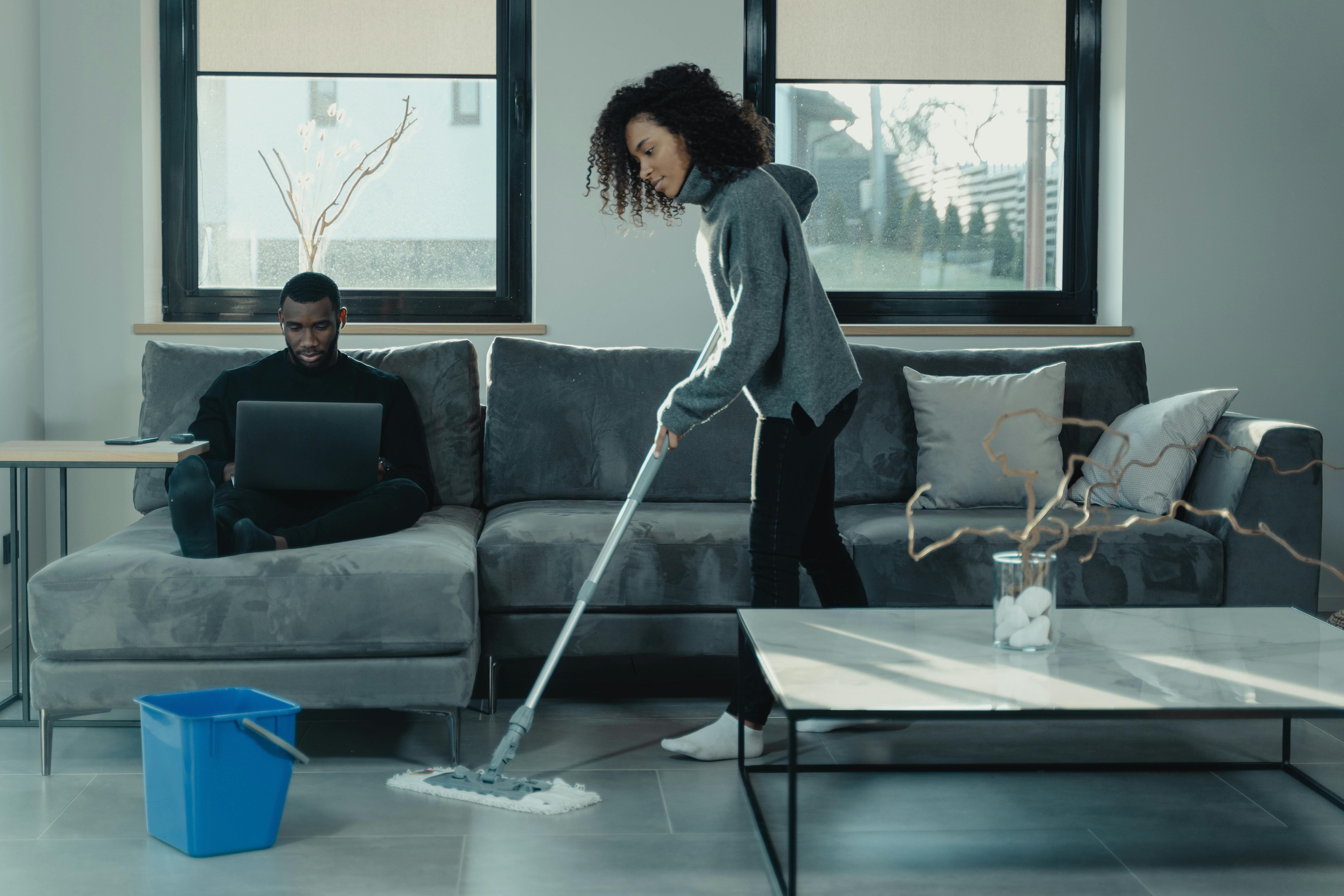 woman in gray long sleeve shirt and black pants holding white mop