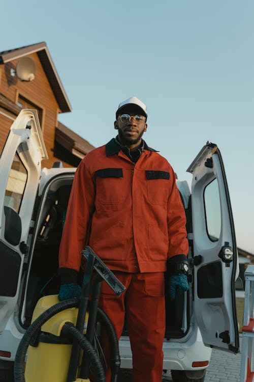 Man in Orange Jacket Standing Beside Gray Suv