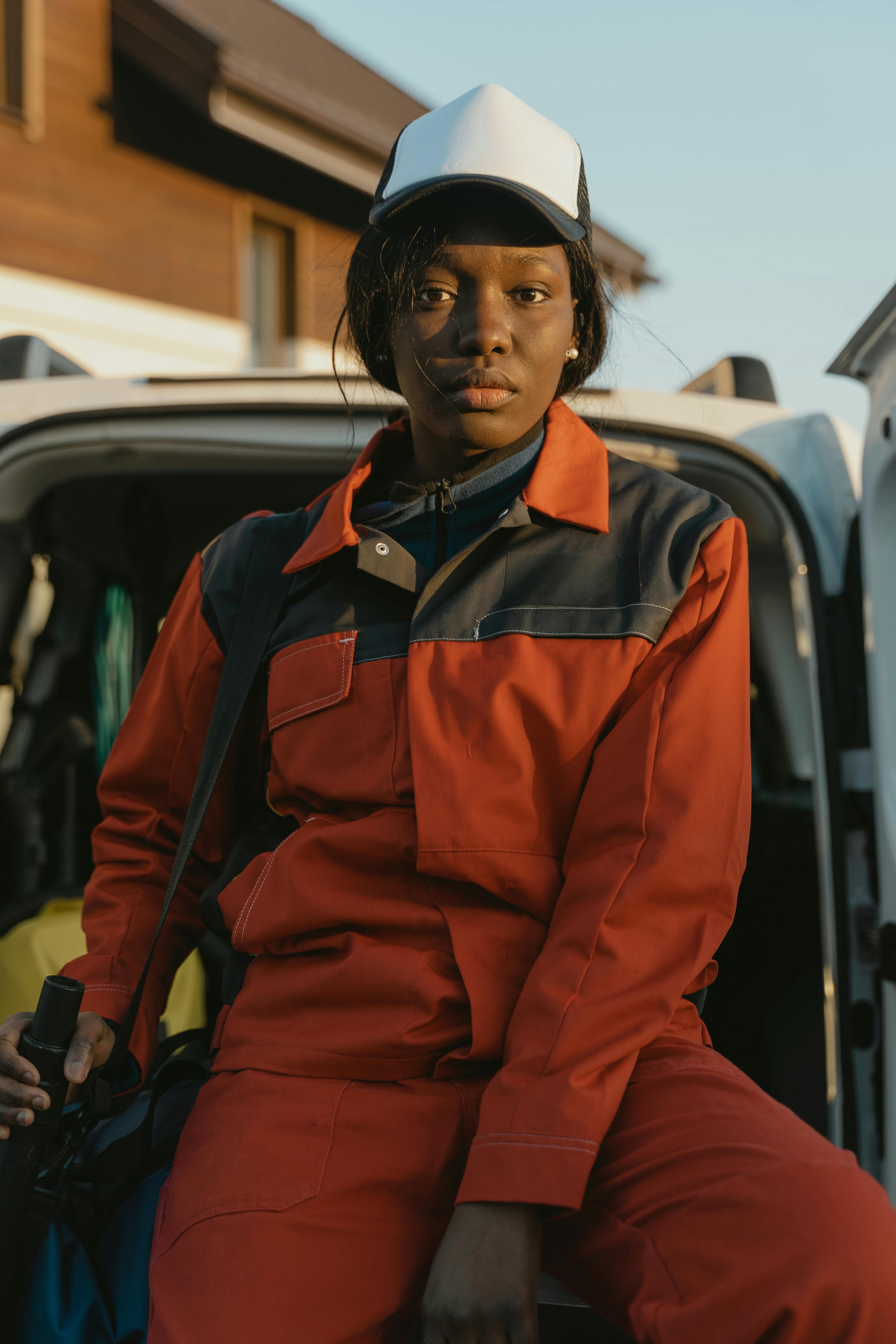 man in red button up jacket standing beside black car