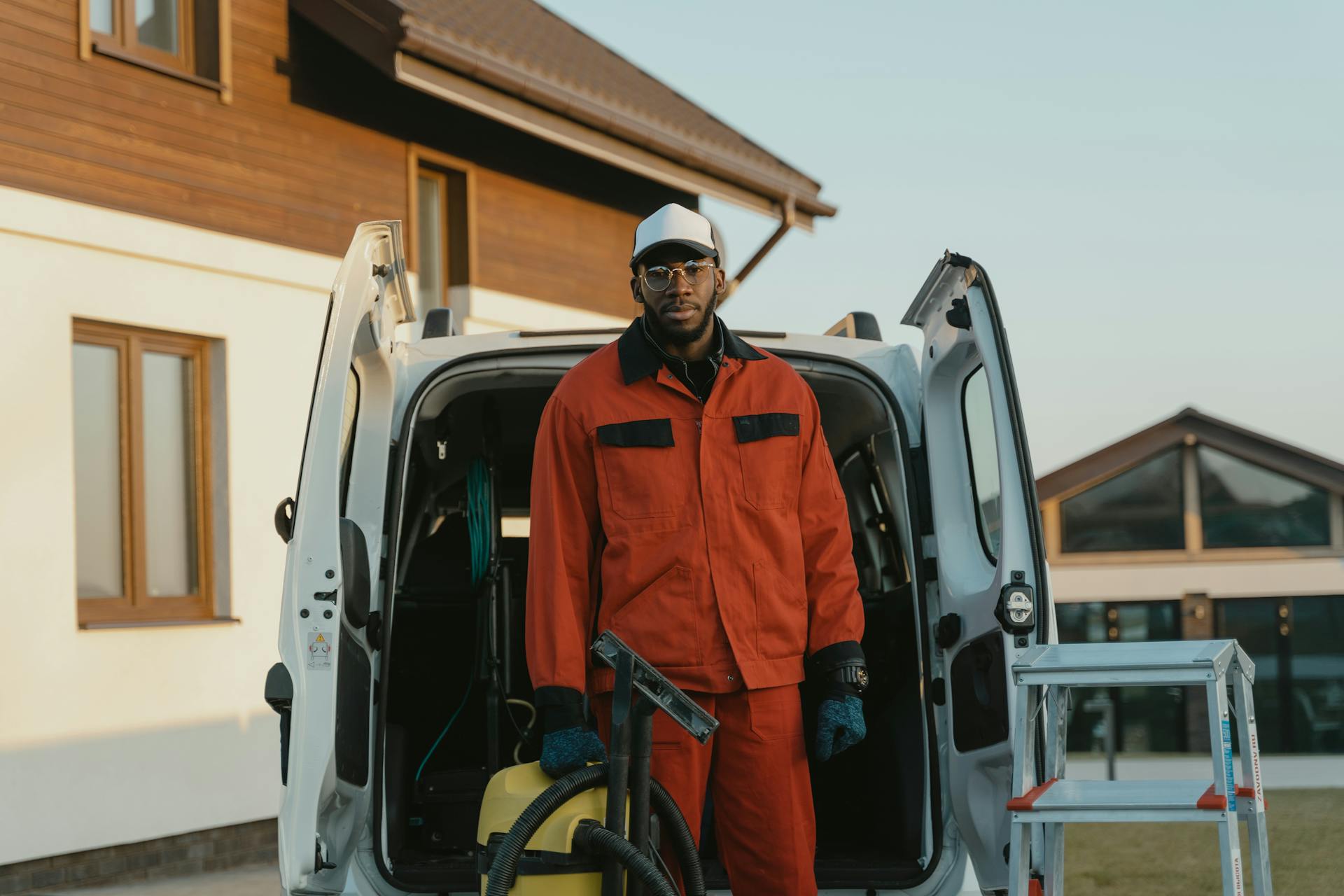 Man in Orange Jacket Standing Beside White Van