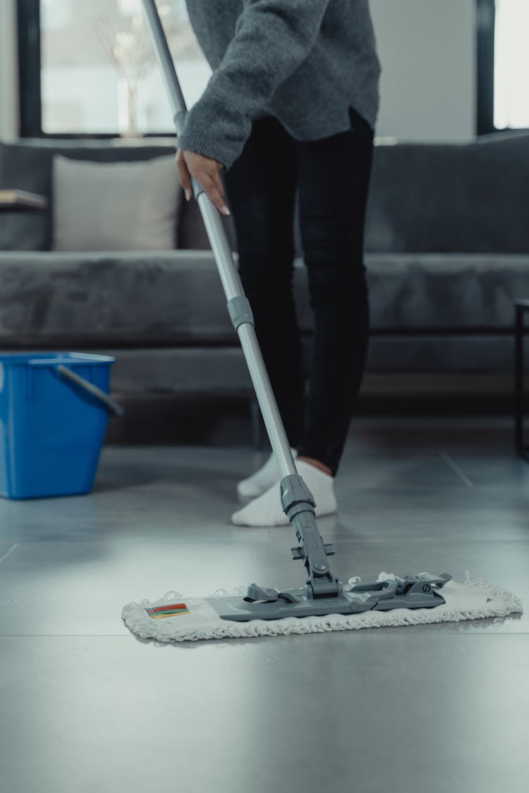 Person In Gray Sweater Mopping And Cleaning The Floor