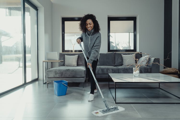 Woman In Gray Sweater Mopping A Tiled Floor