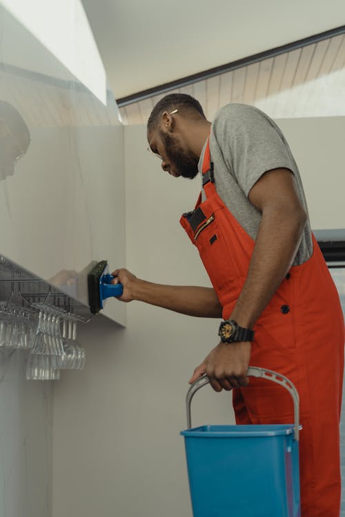 A Man in Gray Shirt Cleaning the Wall