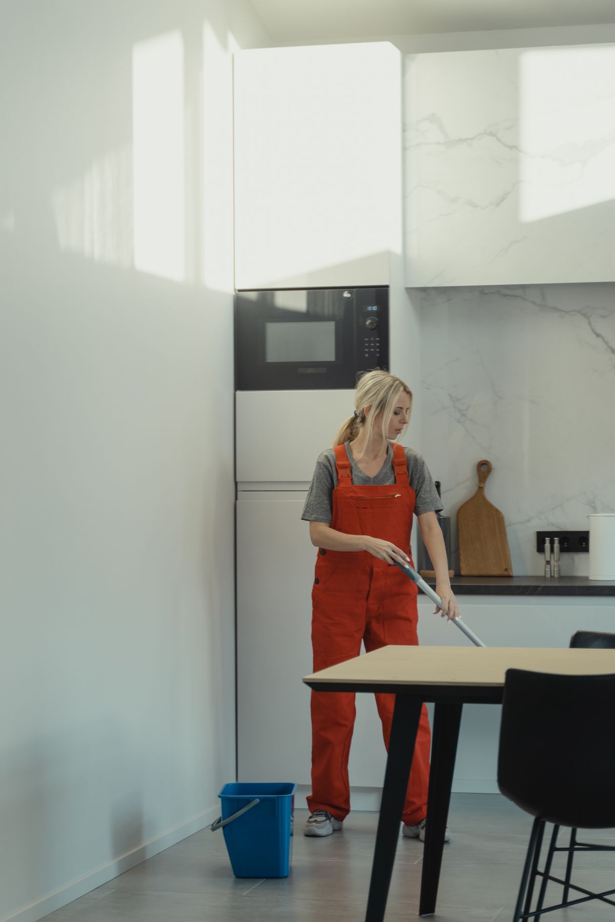 Woman mopping a kitchen floor with a mop and bucket