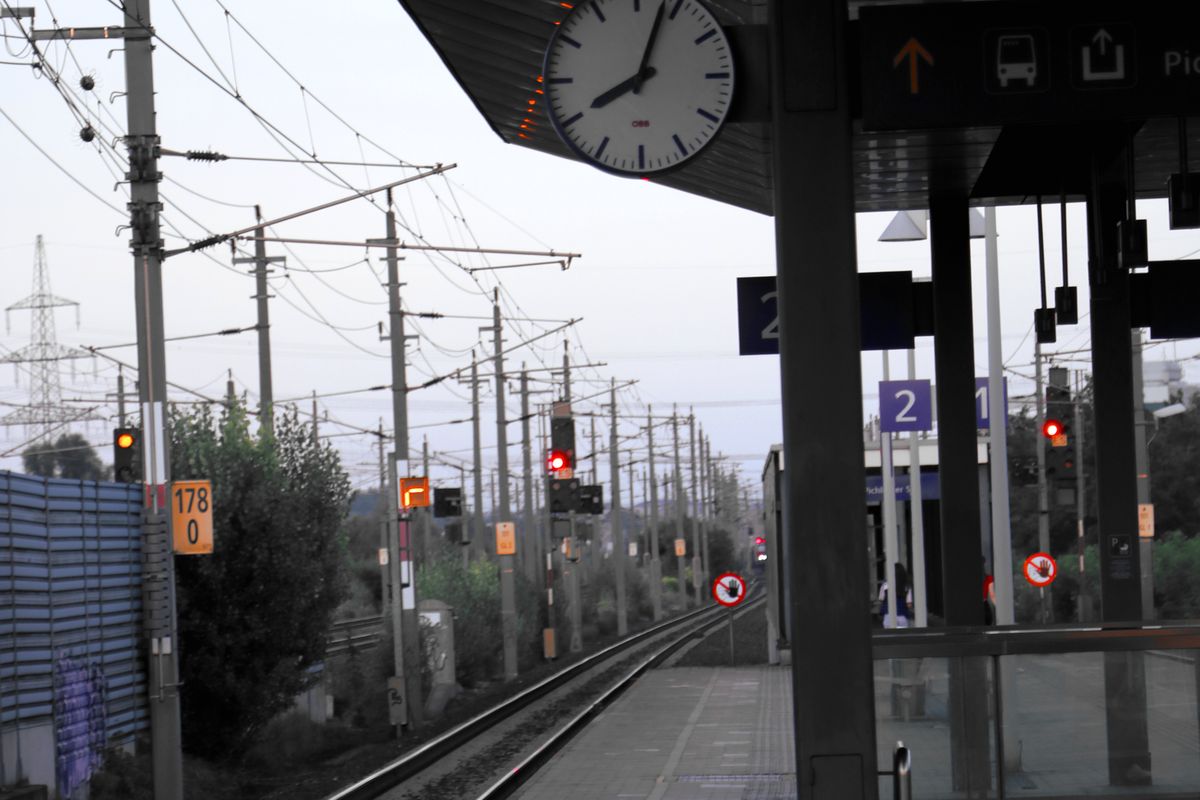 Station platform with a clock and train tracks
