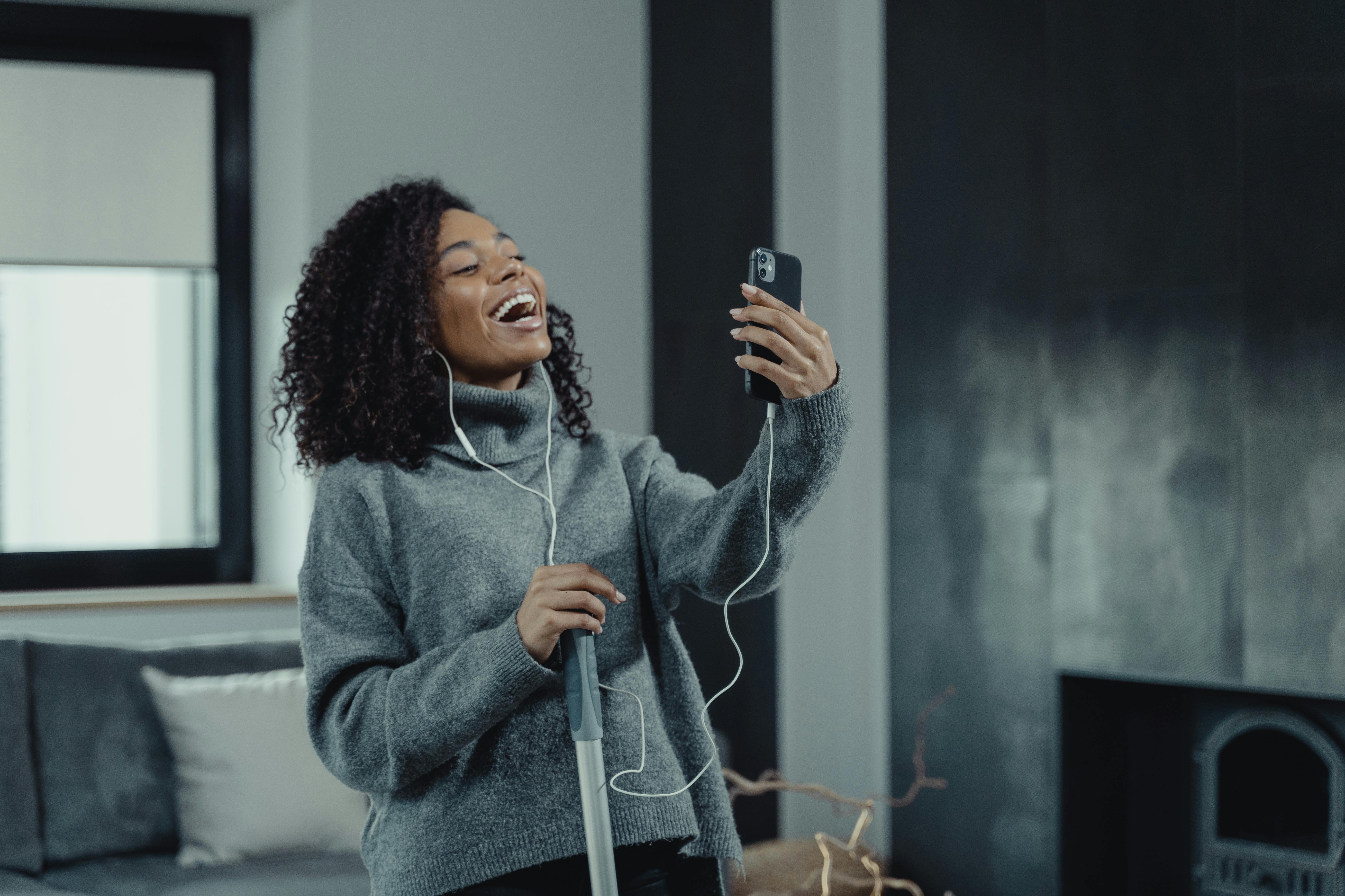 woman in gray sweater laughing while on a video call