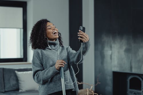 Free Woman in Gray Sweater Holding Black Smartphone Stock Photo