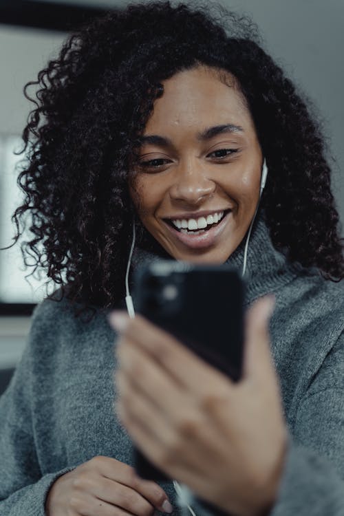 Pregnant woman in sports bra using smart phone in doorway - Stock