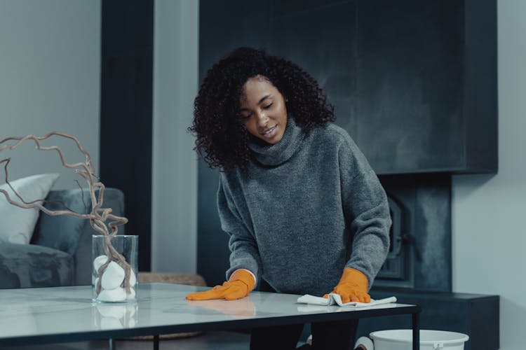 A Woman In Gray Sweater Wiping The Table