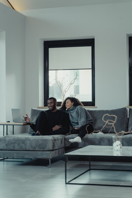 Free A Couple Sitting on the Couch while Looking at the Laptop Stock Photo