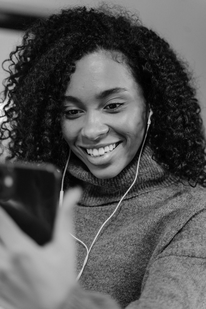 Black and white portrait of a woman smiling during a video call on her smartphone.