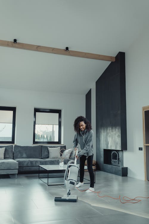 Woman in White Long Sleeve Shirt Standing Near Gray Couch