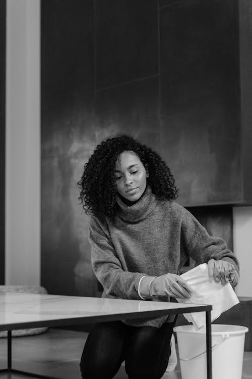 Woman in Sweater Cleaning a Table