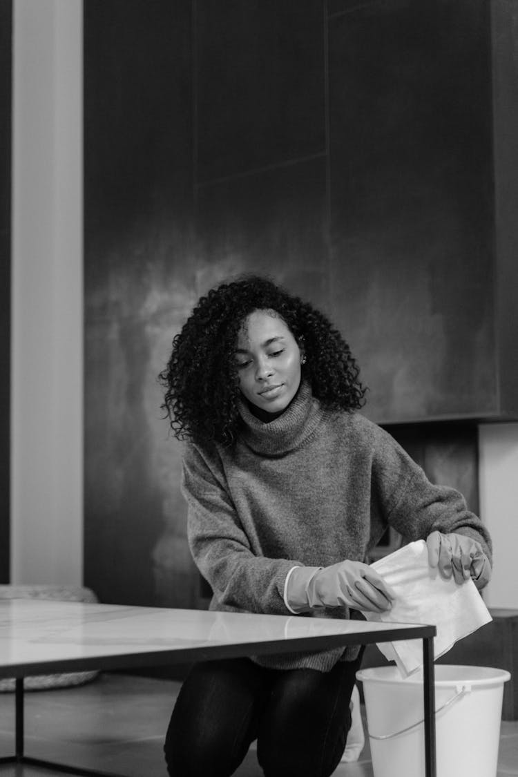 Woman In Sweater Cleaning A Table