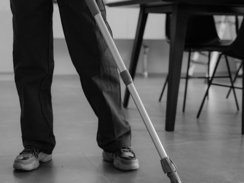 A cleaner mopping a tiled floor indoors