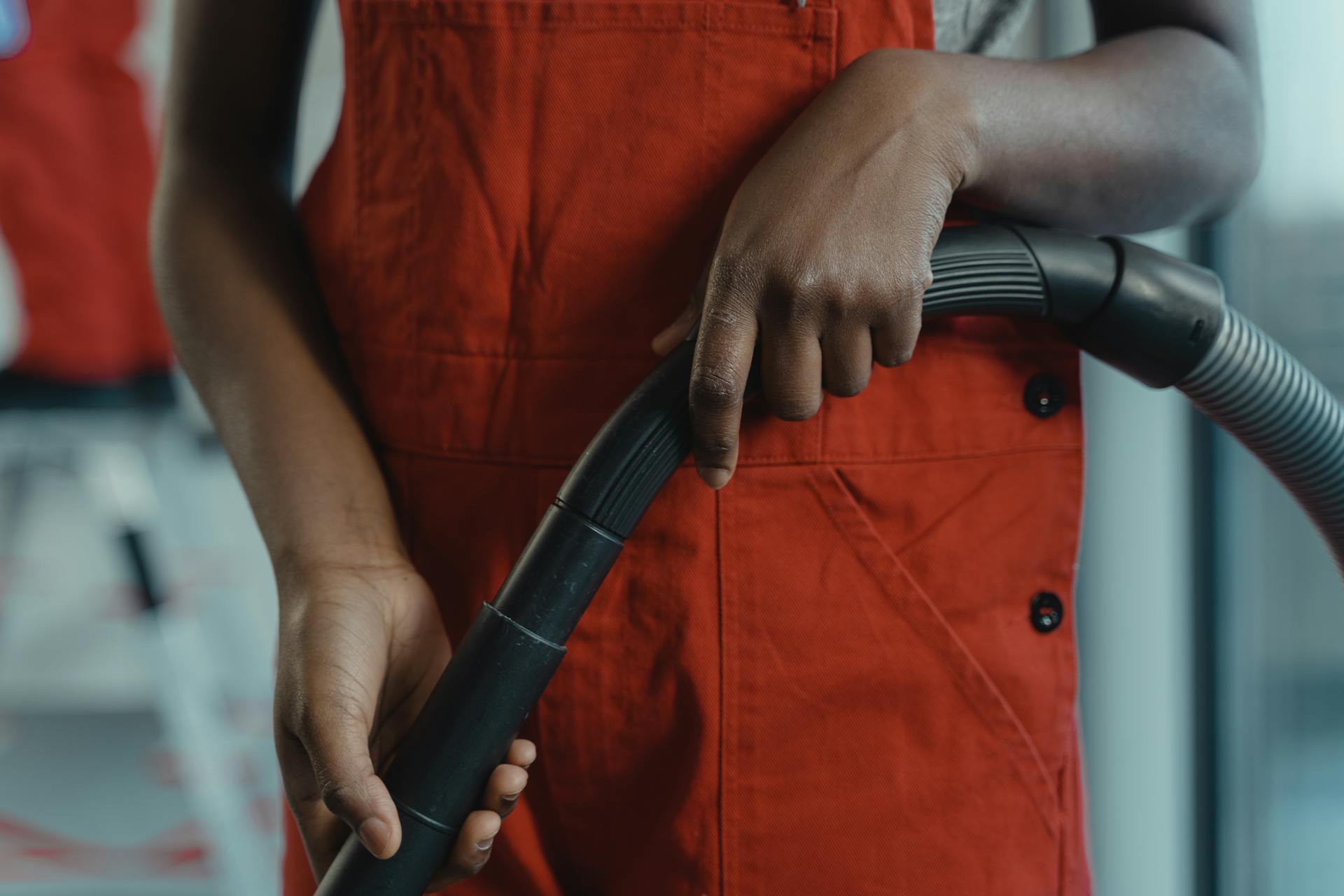 Person in Red Jumper Holding a Vacuum Hose