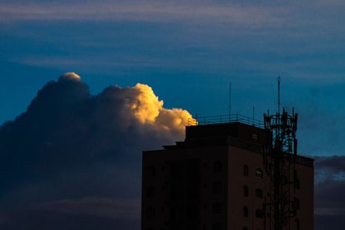 Free Part of tall residential building with metal constructions located on street against blue sky with white cumulus clouds in city Stock Photo