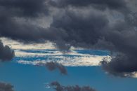 Dark cumulus and spindrift clouds on blue sky