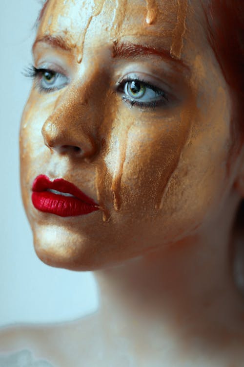 A Woman With Red Lips and Gold Paint on Her Face