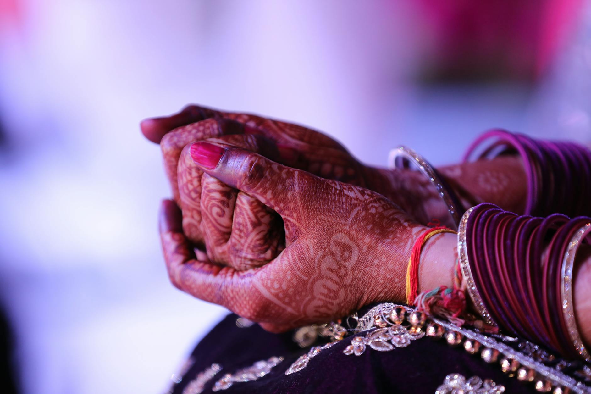 Detailed view of clasped hands adorned with henna and colorful bangles, showcasing traditional Indian culture.